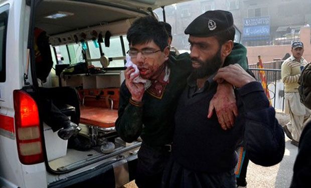 A hospital security guard helps a student injured in the shootout at a school under attack by Taliban gunmen in Peshawar, Pakistan,Tuesday, Dec. 16, 2014. Taliban gunmen stormed a military school in the northwestern Pakistani city, killing and wounding dozens, officials said, in the latest militant violence to hit the already troubled region.